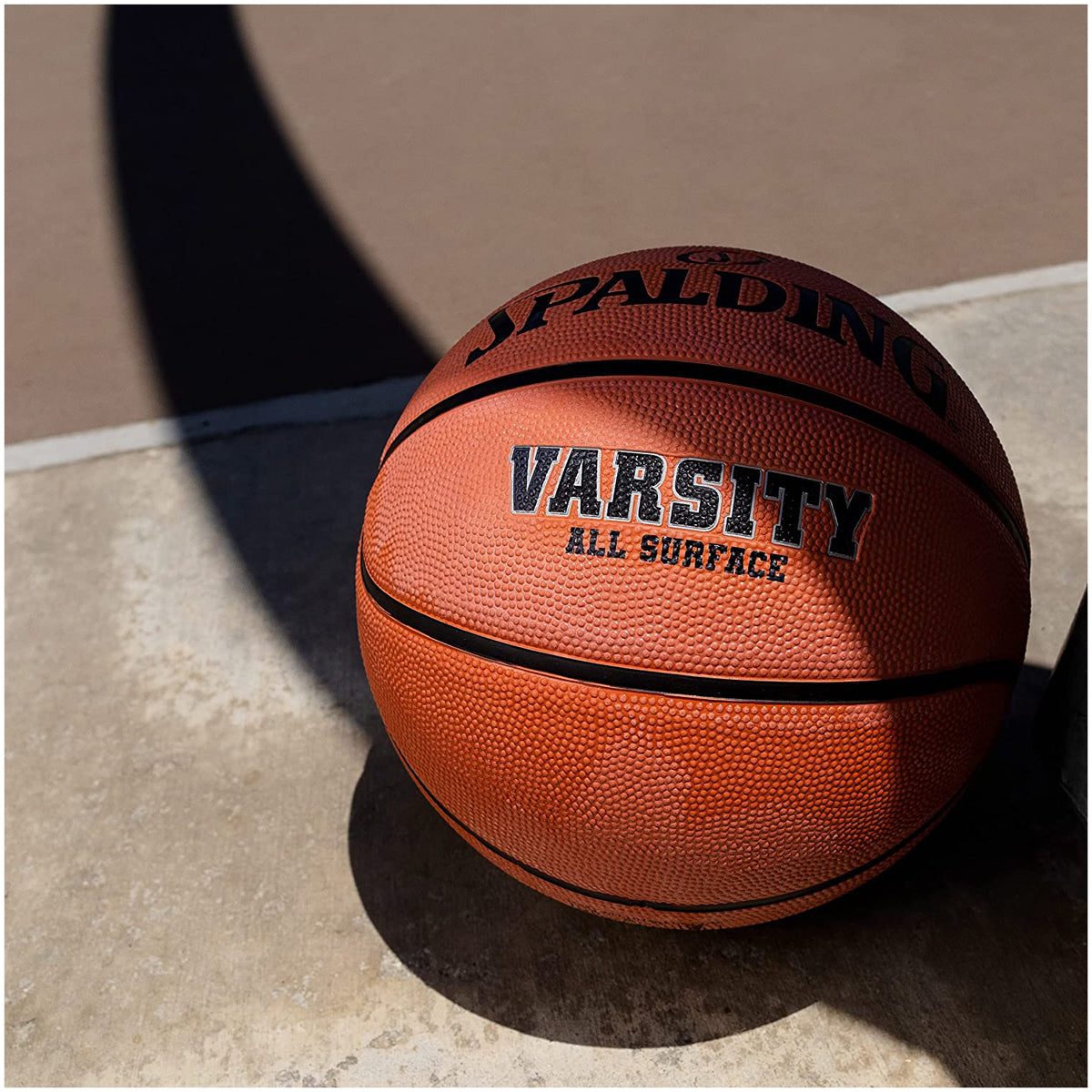 Basketball with 'Spalding Varsity All Surface' text on a concrete floor.