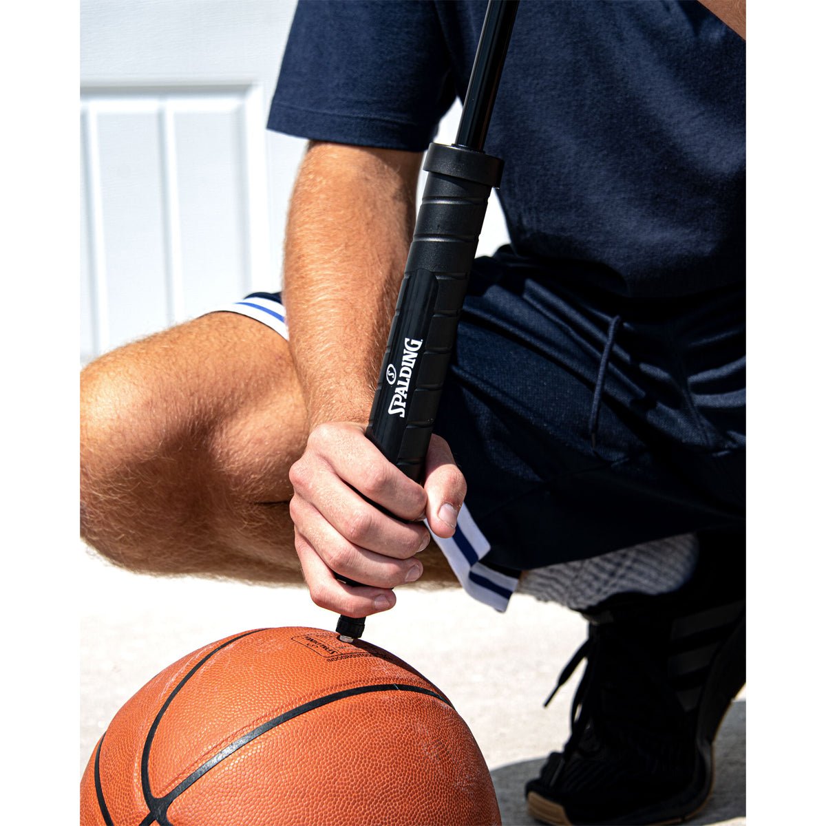 Person using a dual action air ball pump to inflate a basketball