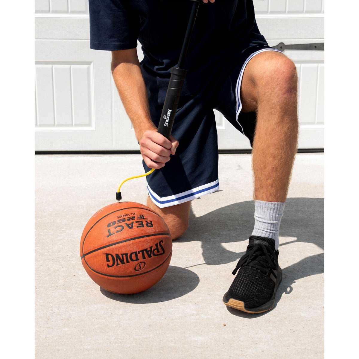 A person inflates a basketball with dual action air ball pum and prepares to shoot.