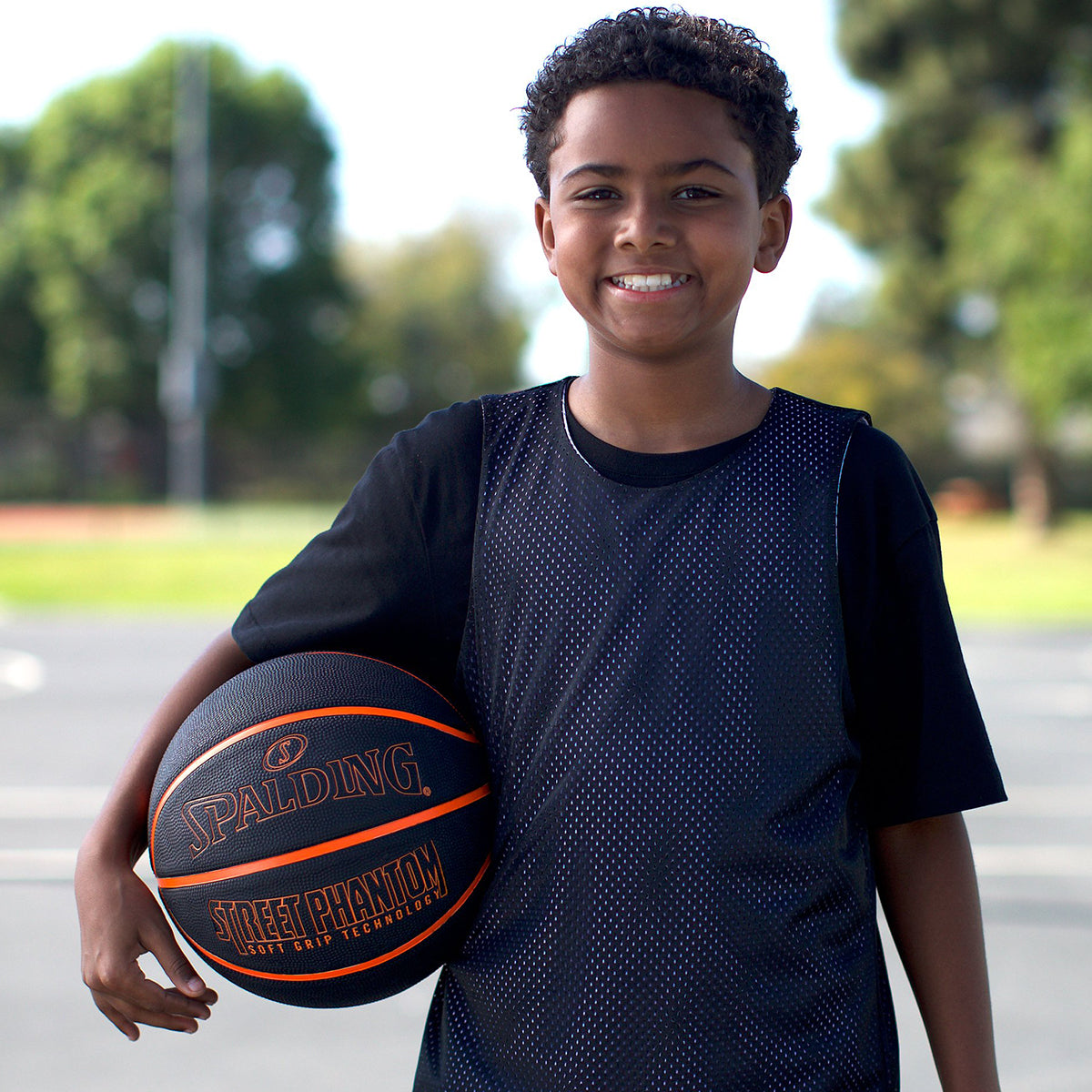 Young boy holding a Spalding basketball outdoors