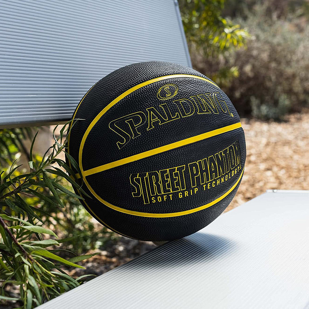 Black and yellow Spalding Street Phantom basketball on a surface outdoors.
