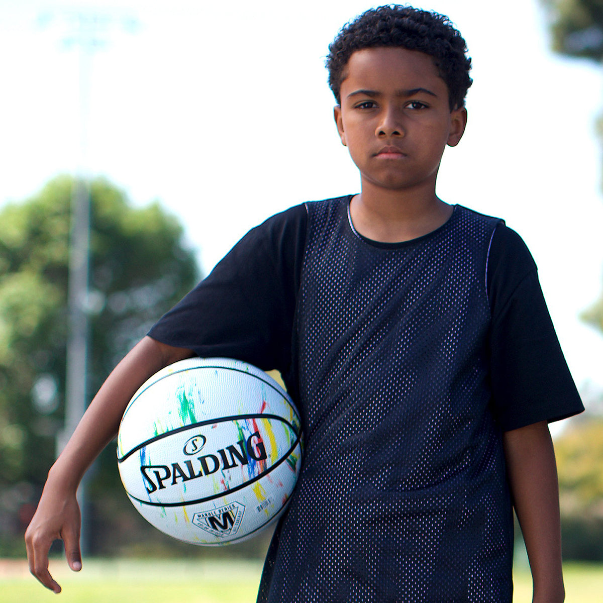 Young boy holding a Spalding basketball outdoors - Forza Sports
