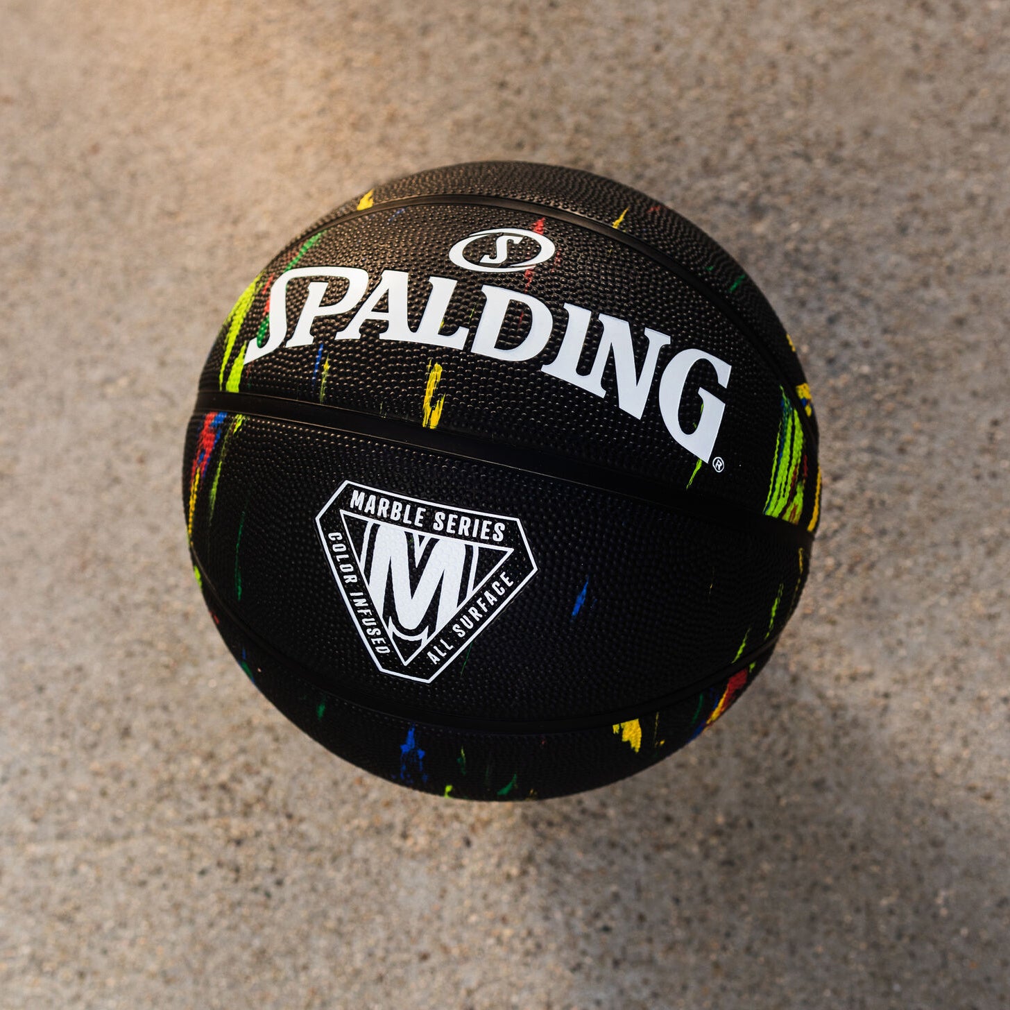 Spalding basketball with colorful speckles on a concrete surface