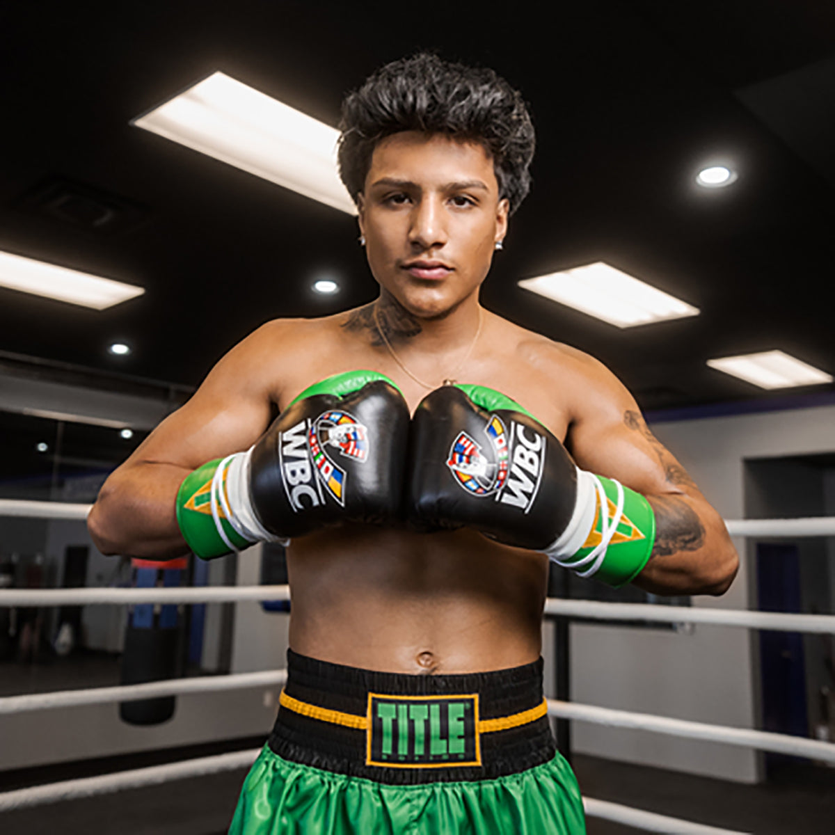 Boxer in a boxing ring wearing green and black boxing gloves and shorts with WBC and TITLE branding.