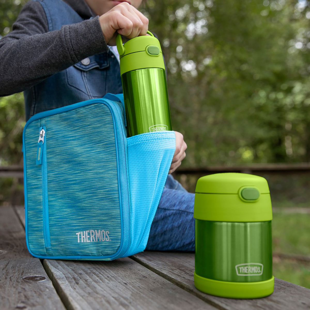 Green Thermos food jar with blue carrying case on a wooden surface