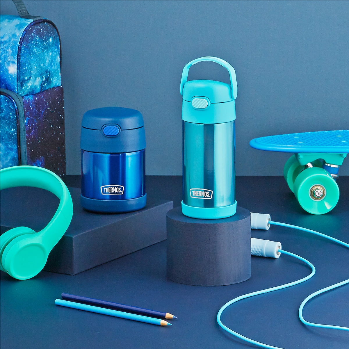 Blue thermos, water bottle, and scooter on a blue background