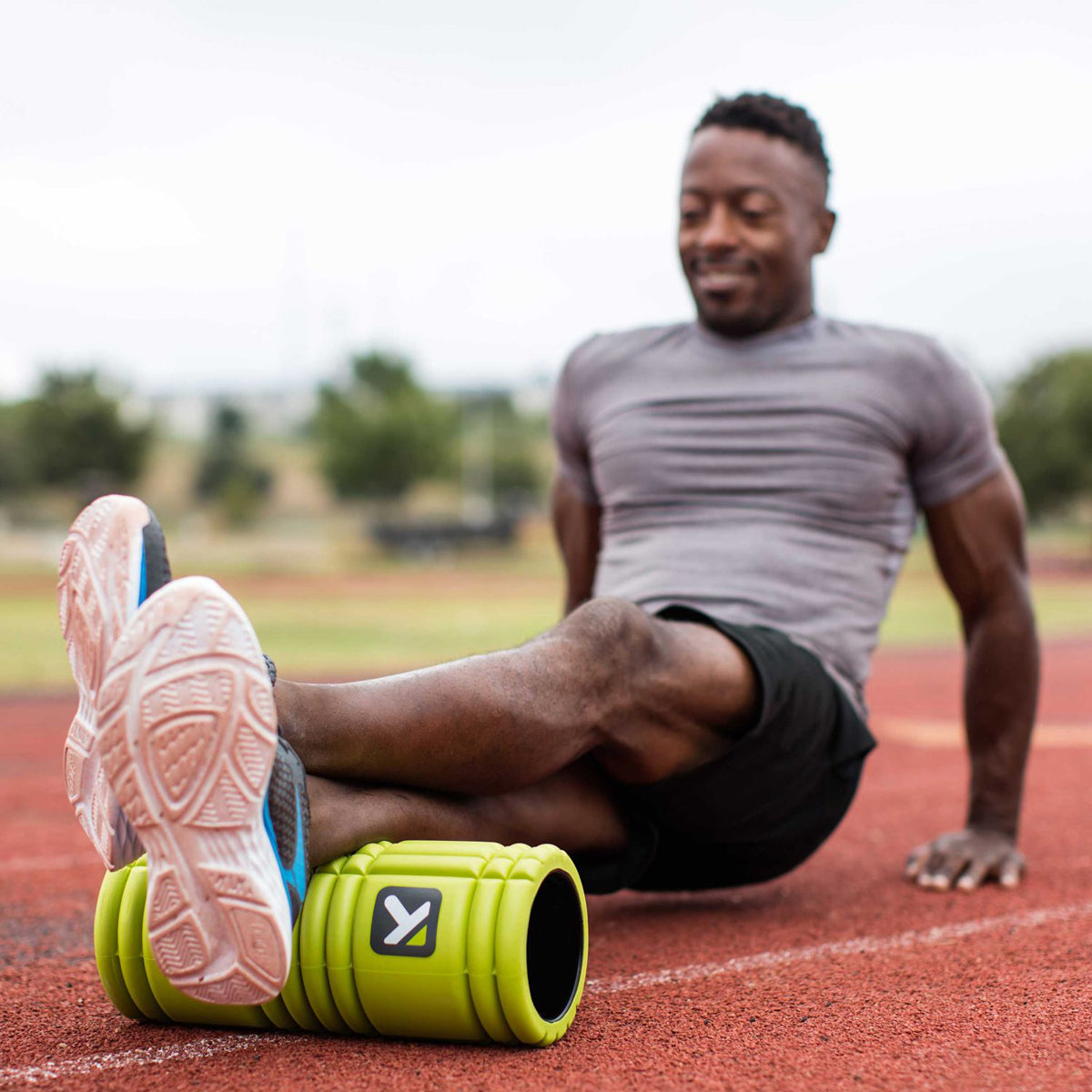 Man using a massage roller for sore muscles in green color