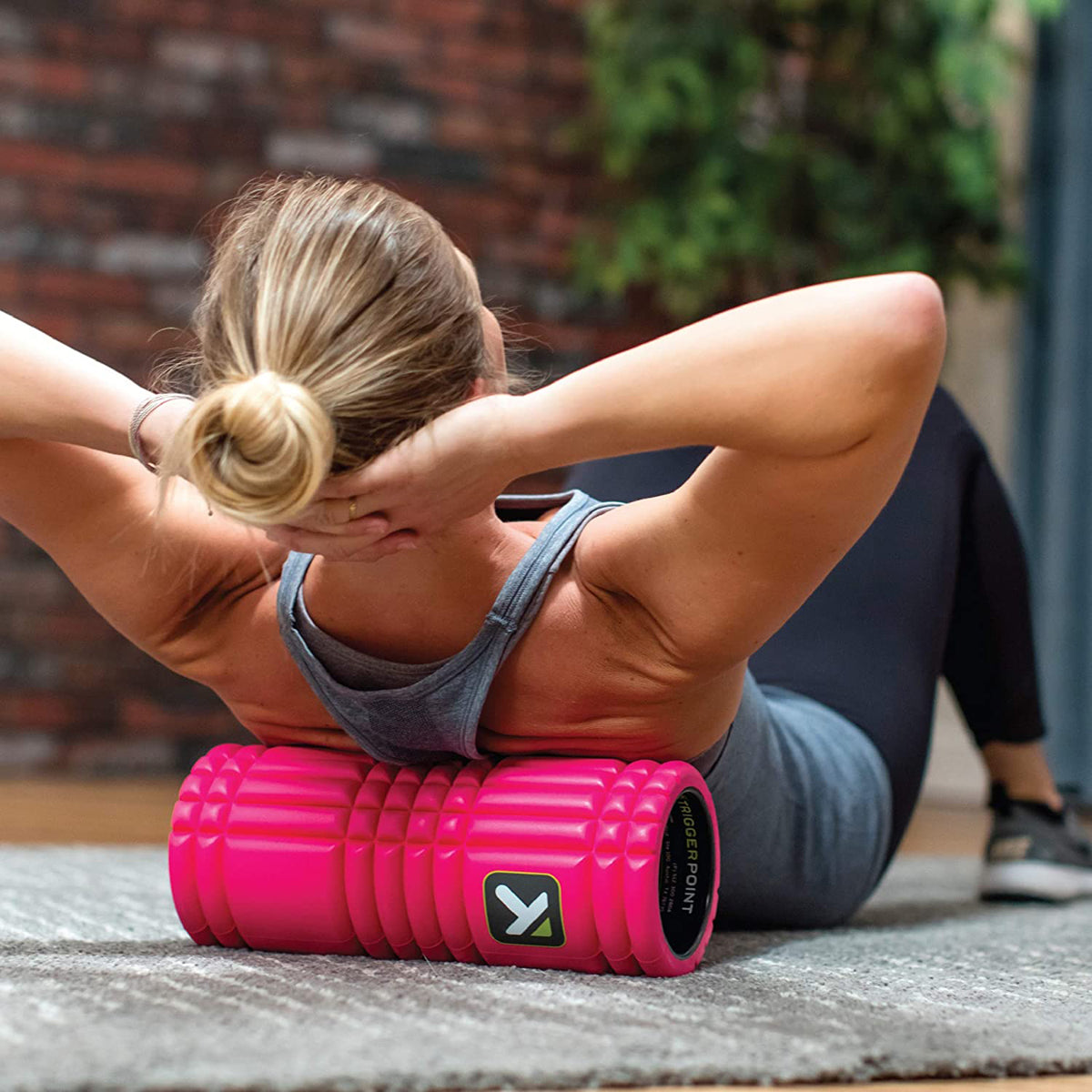 Woman using a pink foam roller myofascial release - Forza Sports