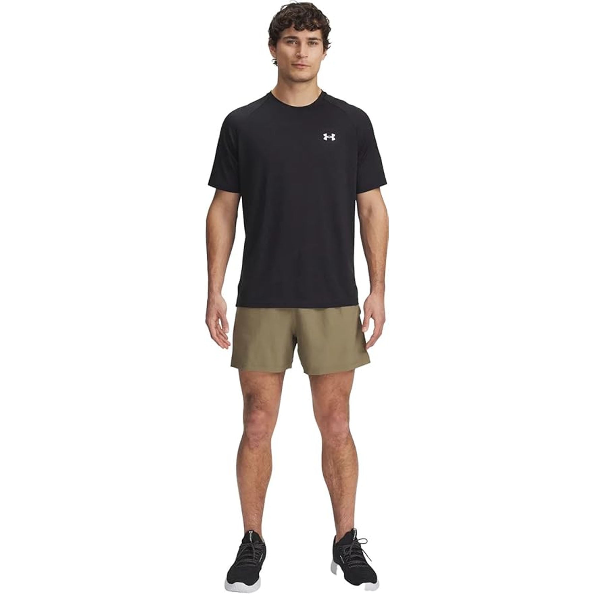 Man wearing a black t-shirt with a logo and beige woven shorts on a white background