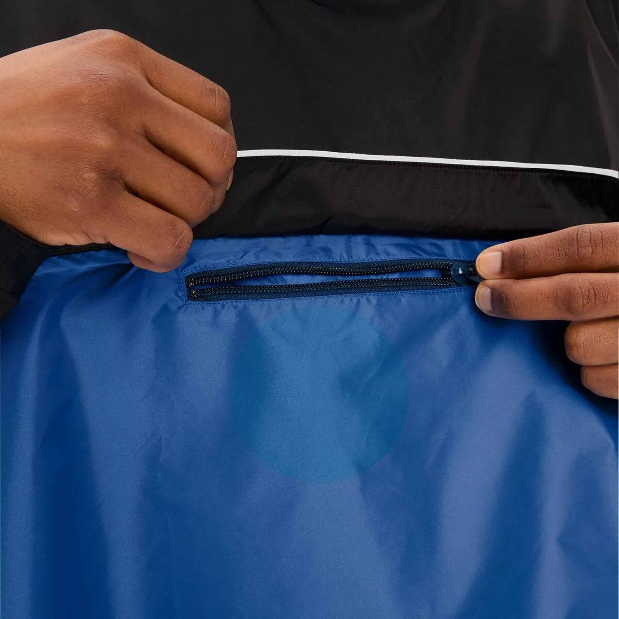Person zipping a blue biking rain jacket with a black zipper, wearing a black shirt.