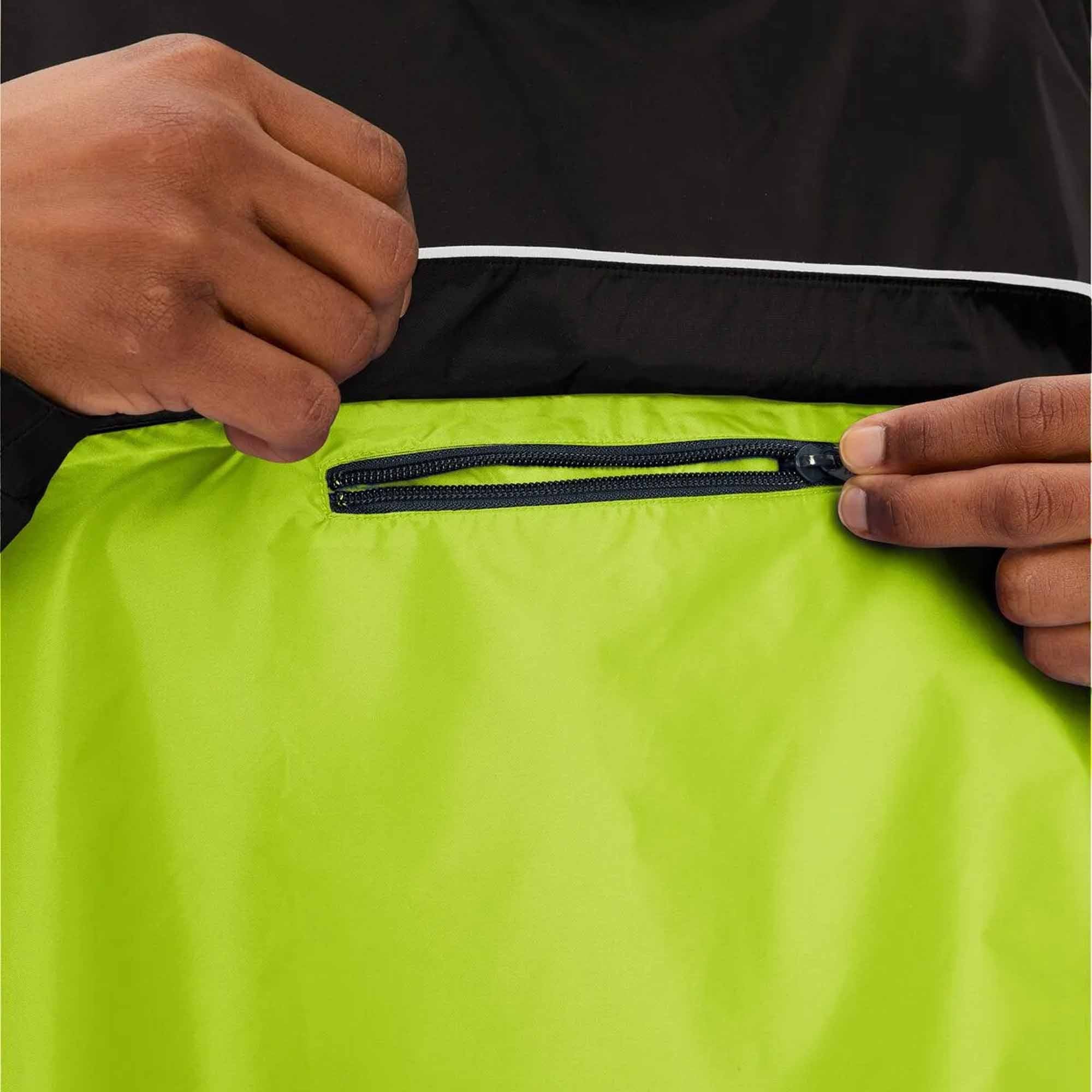 Person zipping a bright green jacket with a black zipper against a black background
