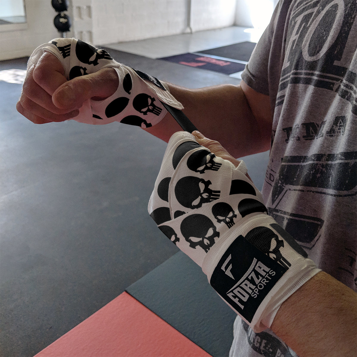 Person wearing boxing wraps with skull design in a gym setting