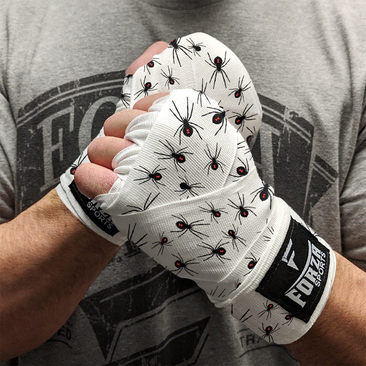Person wearing white boxing gloves with black spider design, holding a fist, on a gray background.