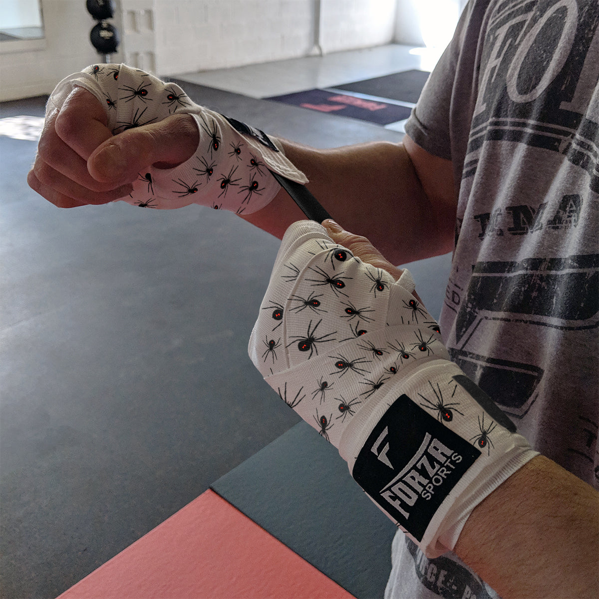 Person wearing boxing gloves with ant pattern in a gym setting
