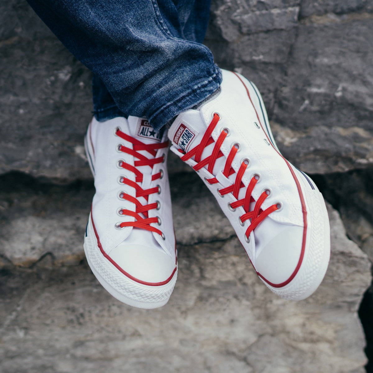 White sneakers with red laces on a rocky surface