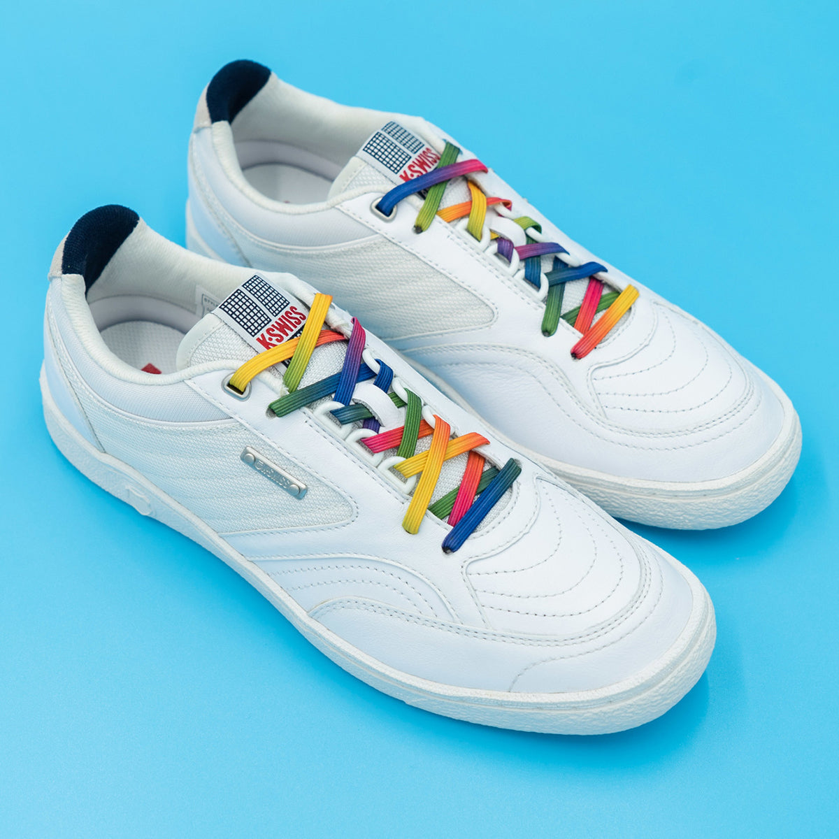 White sneakers with rainbow laces on a blue background