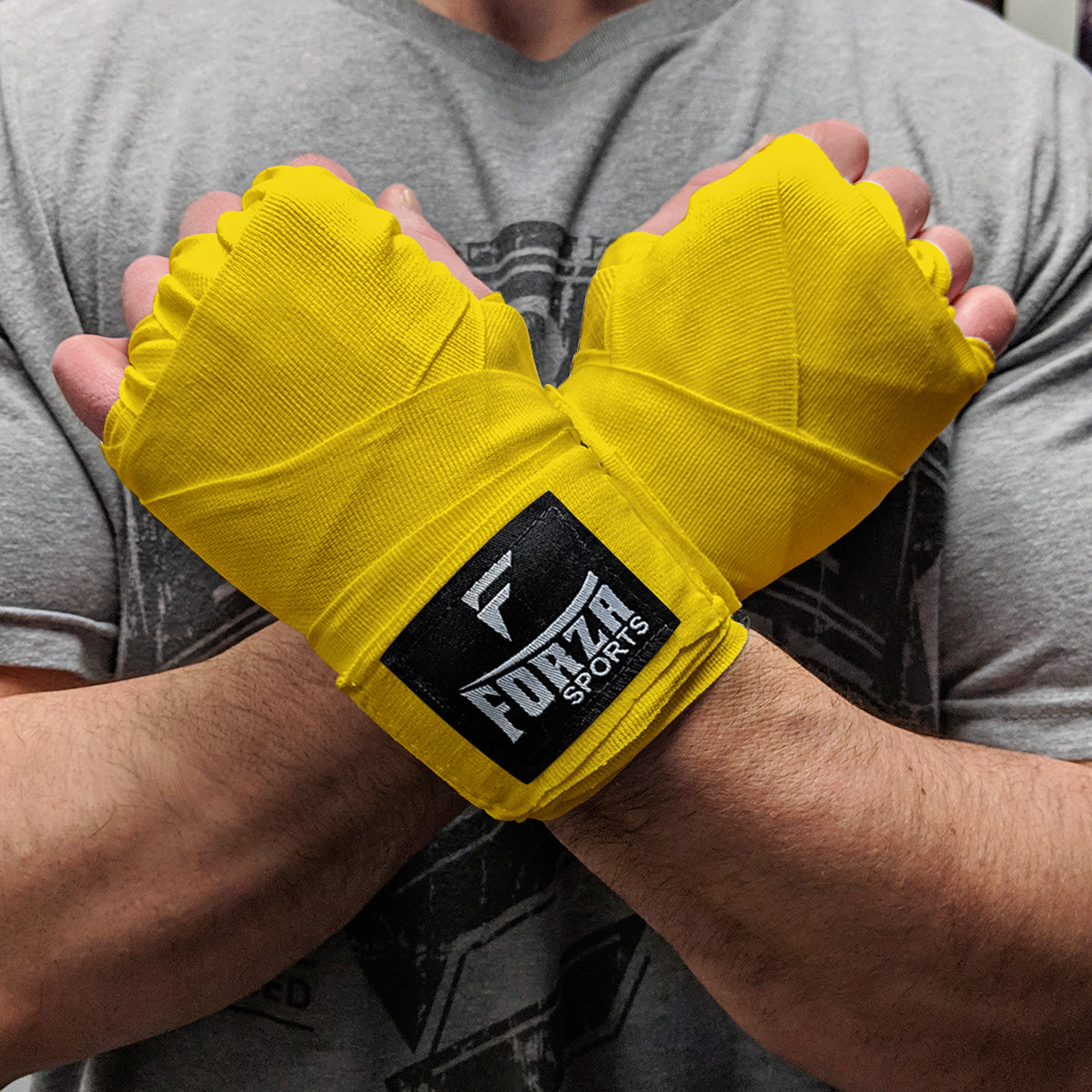 Person wearing yellow boxing hand wraps with Forza Sports logo.