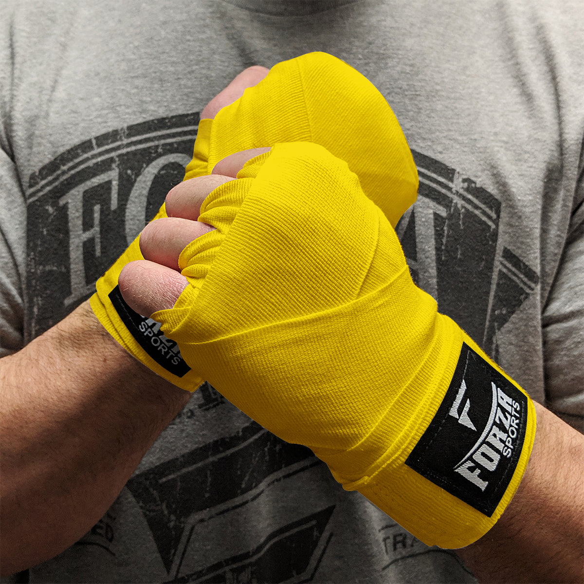 Yellow boxing hand wraps with Forza Sports logo on a person wearing a gray t-shirt.