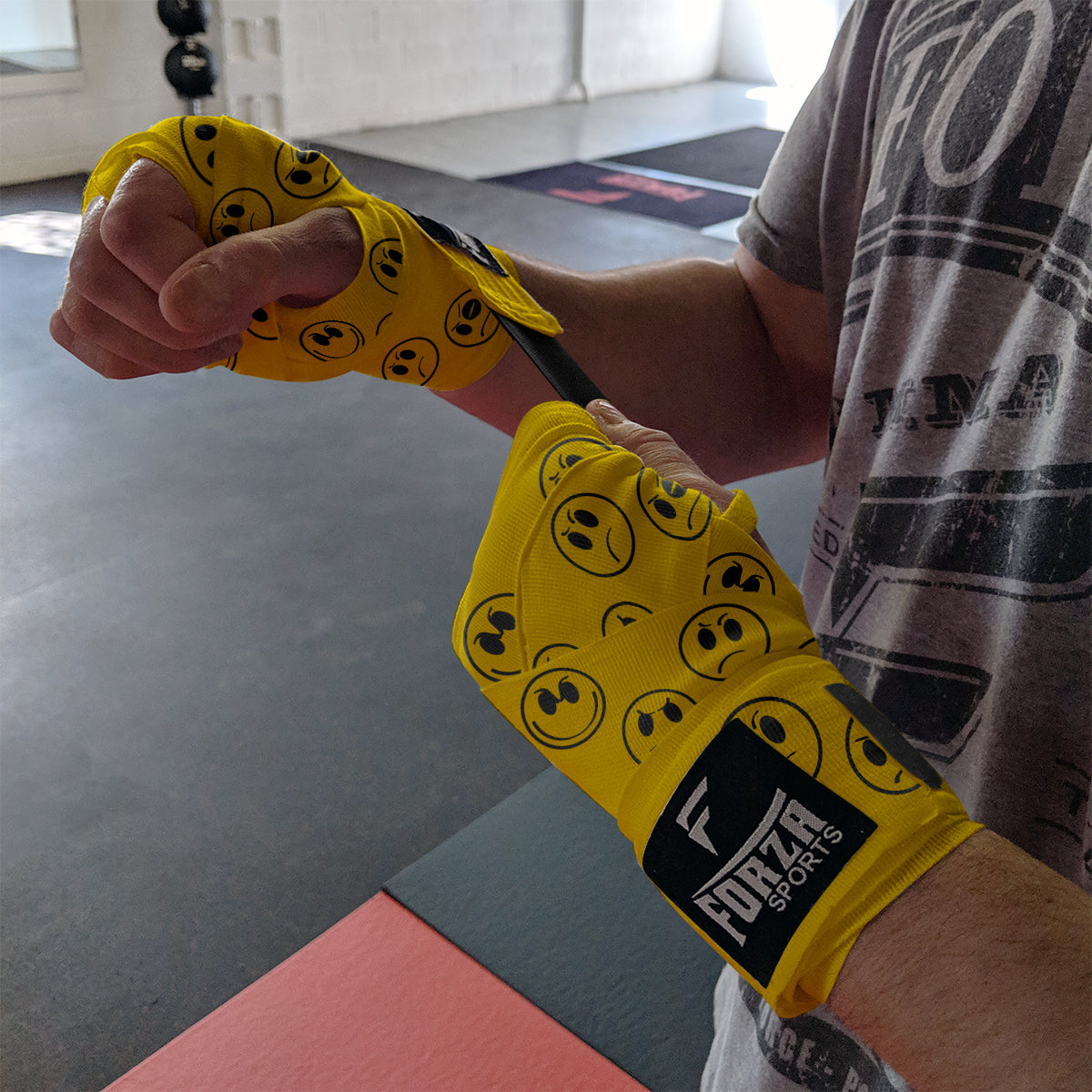 Person wearing yellow boxing wraps with black patterns in a gym setting