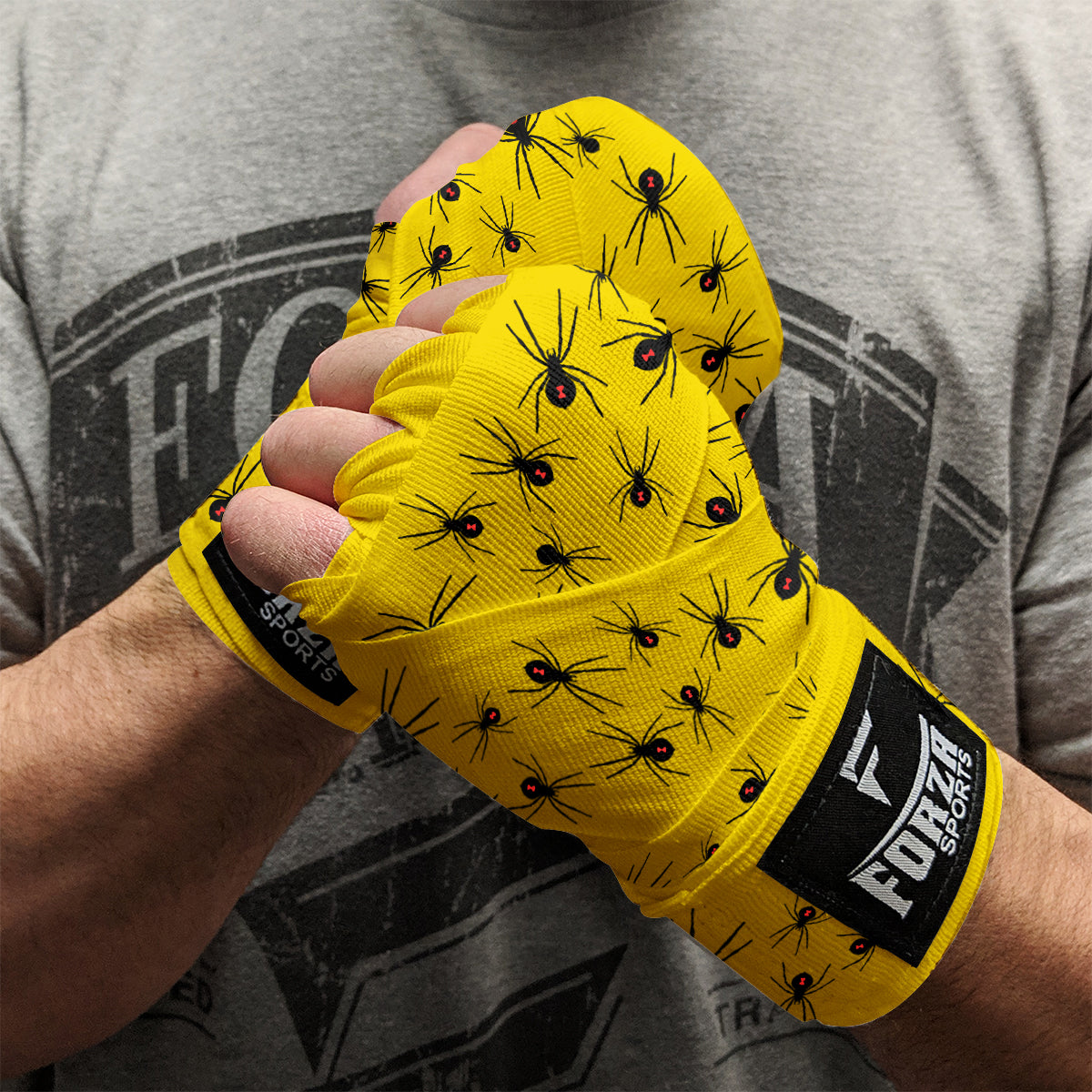 Yellow boxing hand wraps with spider pattern worn by a person, branded 'Forte Sports'.