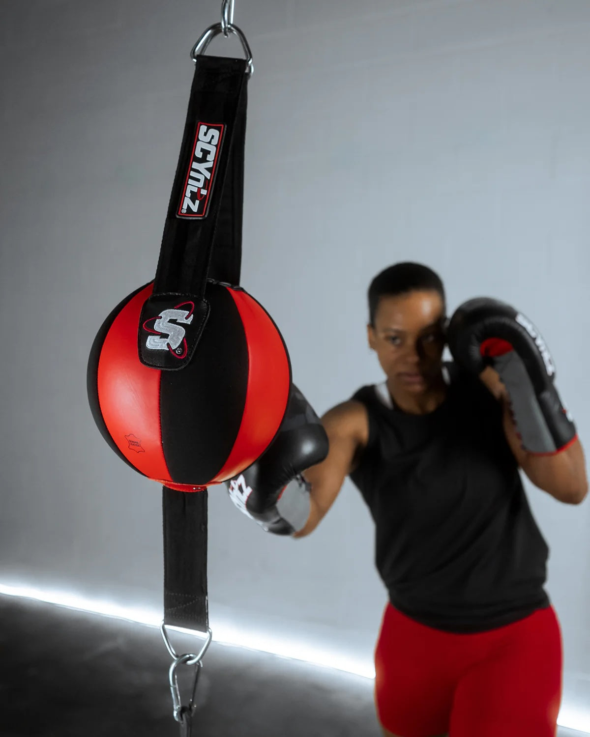 Person wearing boxing gloves and a punching bag with Scyzi branding on a gray background